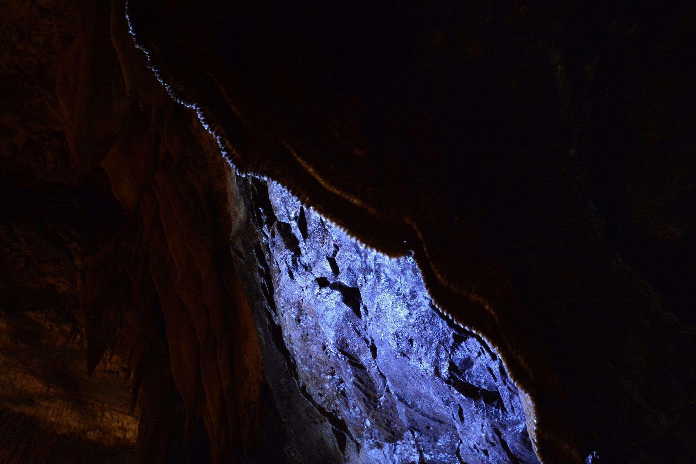 a cave stalactite running diagonally with a purple hue in a wide frame